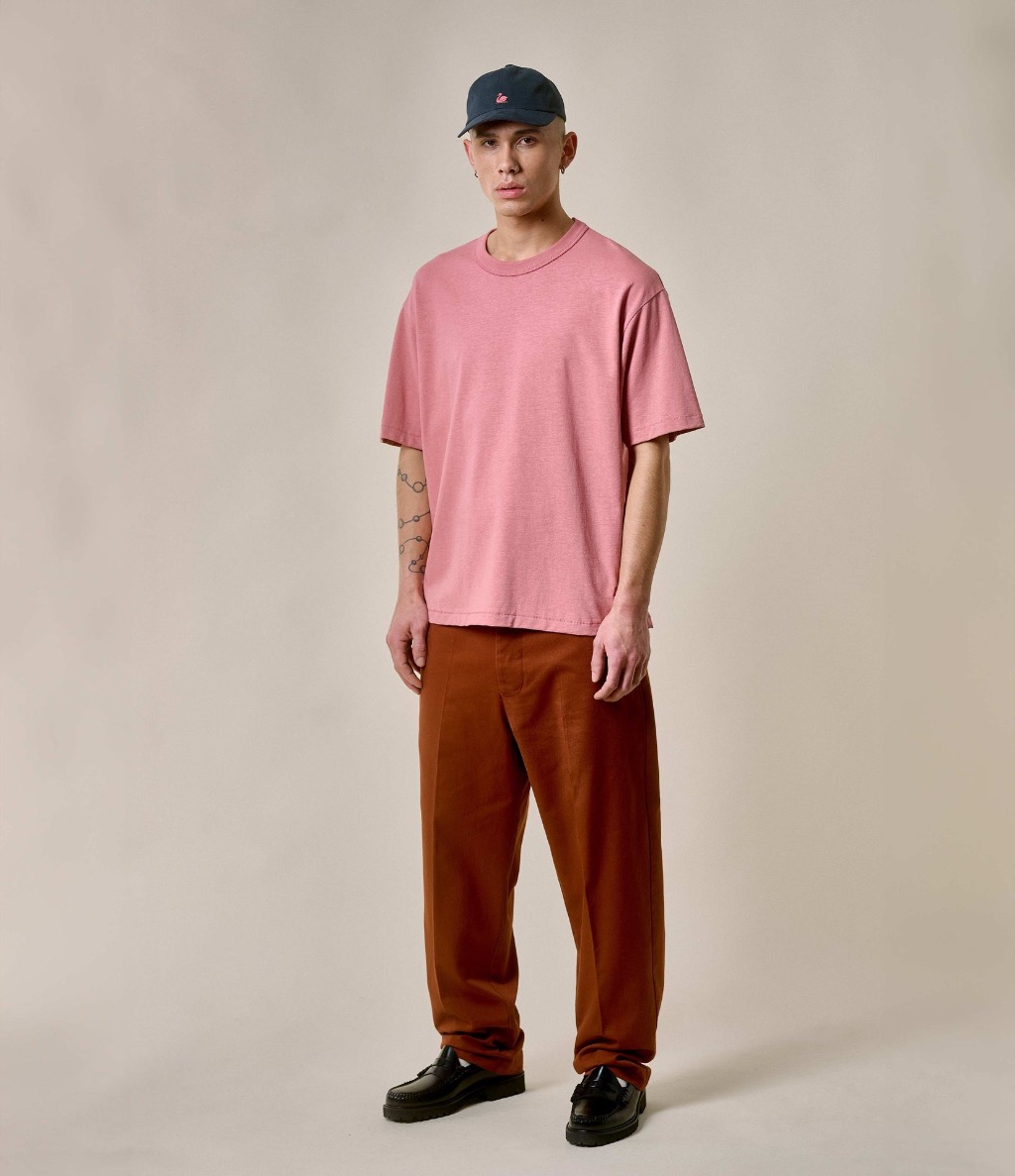 Man wearing pink crewneck T-shirt and brown twill chinos