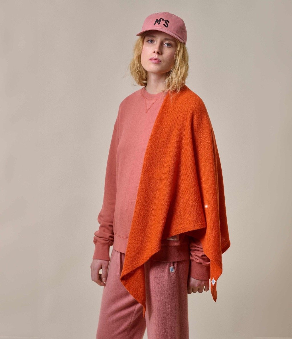 Woman in pink sweatshirt and knit sweatpants wearing orange scarf
