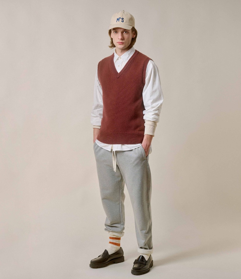 Man wearing brown knit vest and white shirt with grey sweatpants
