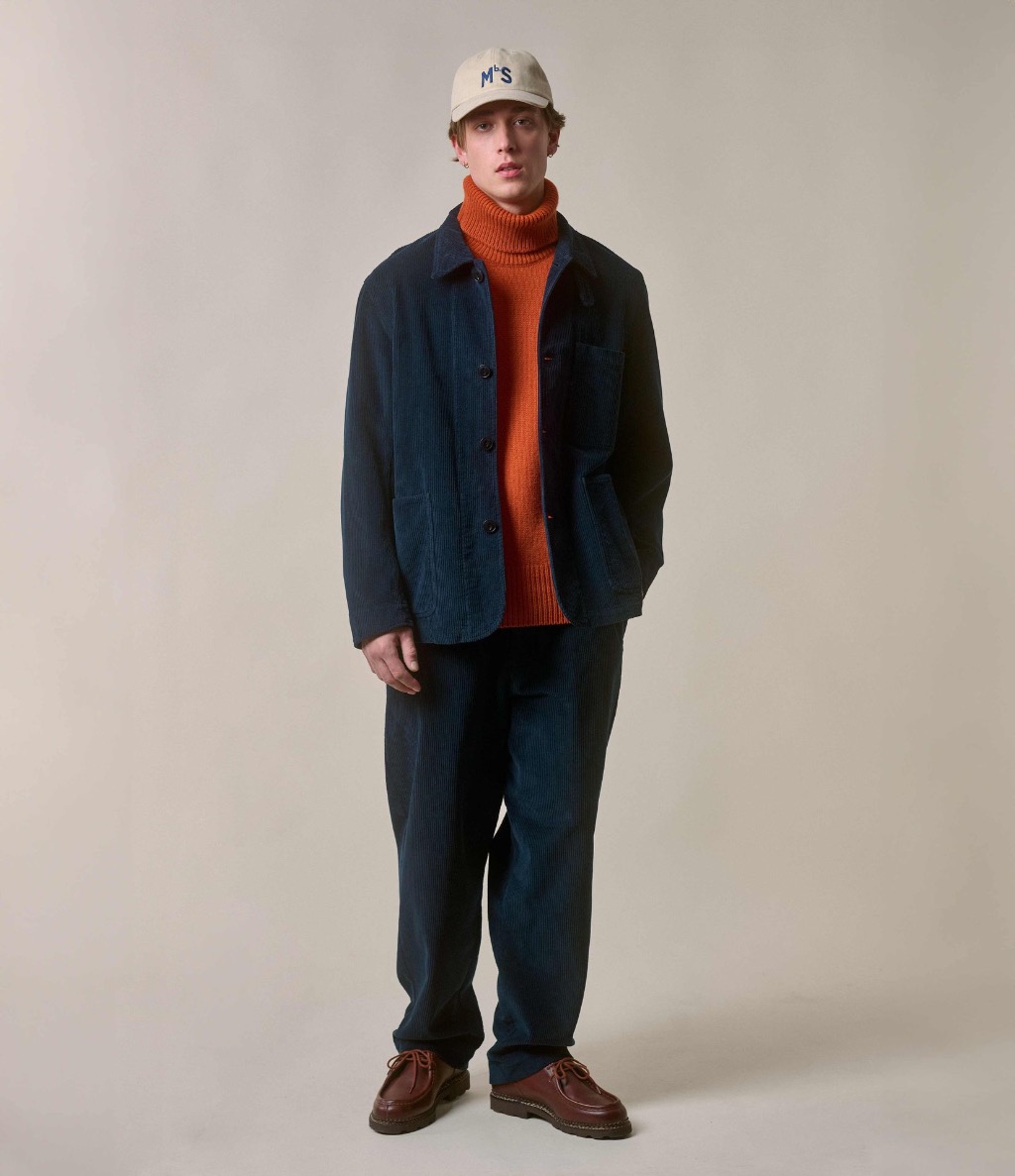 Man wearing blue corduroy jacket and chinos with orange turtleneck