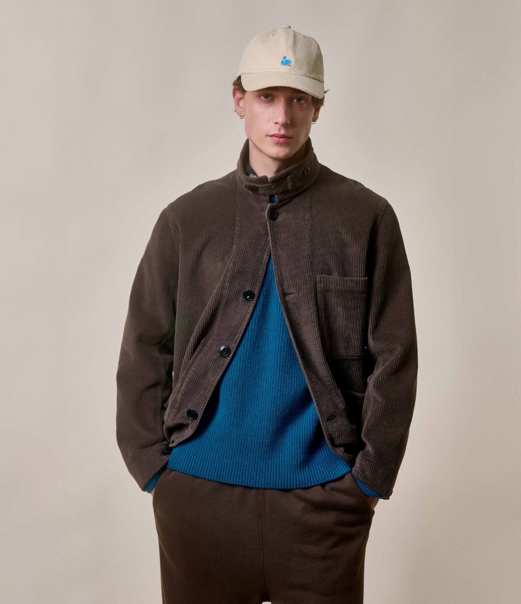 Man wearing brown corduroy jacket over blue crewneck pullover