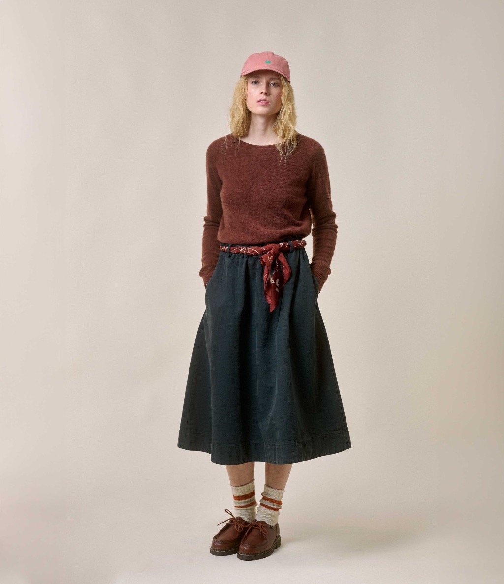 Woman wearing grey twill skirt and brown crewneck pullover