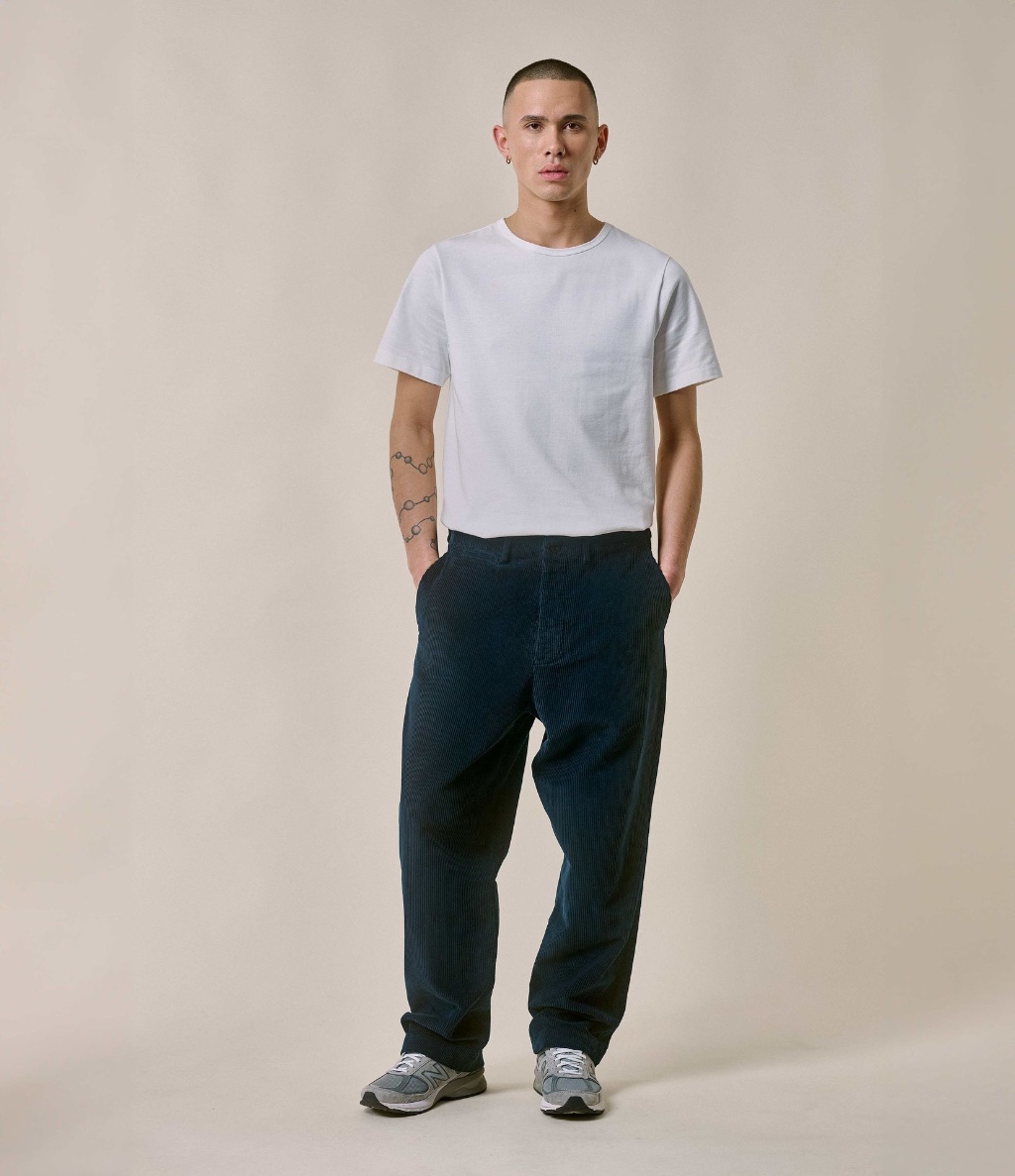Man wearing white crewneck T-shirt and blue corduroy chinos