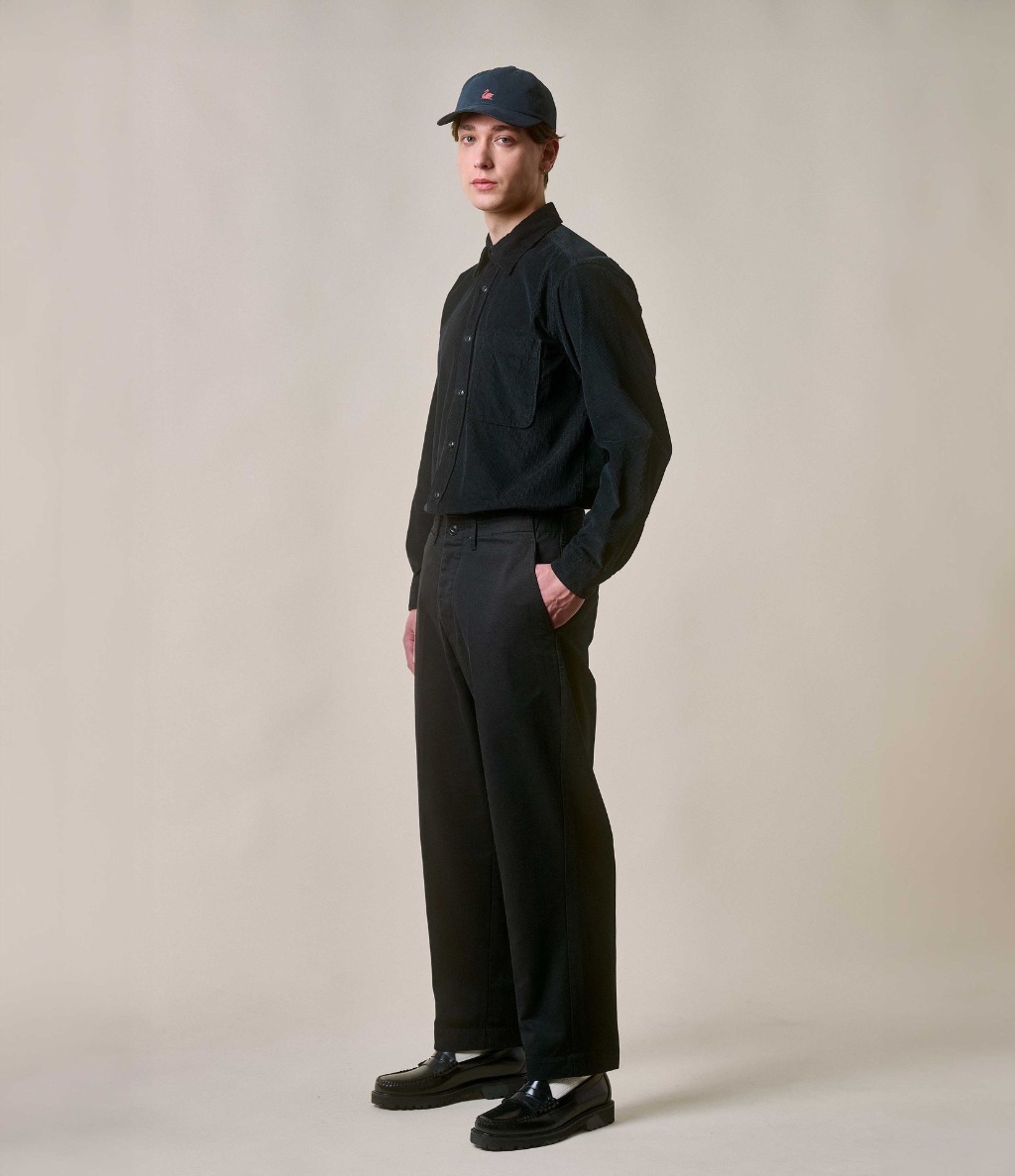 Man with cap wearing black corduroy shirt and twill chinos