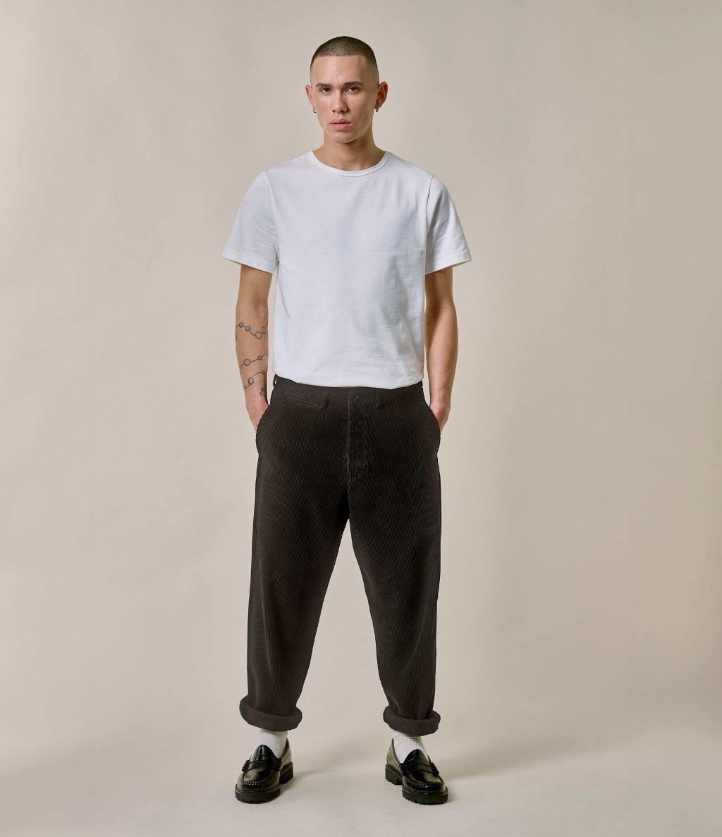 Man wearing white crewneck T-shirt and brown corduroy chinos