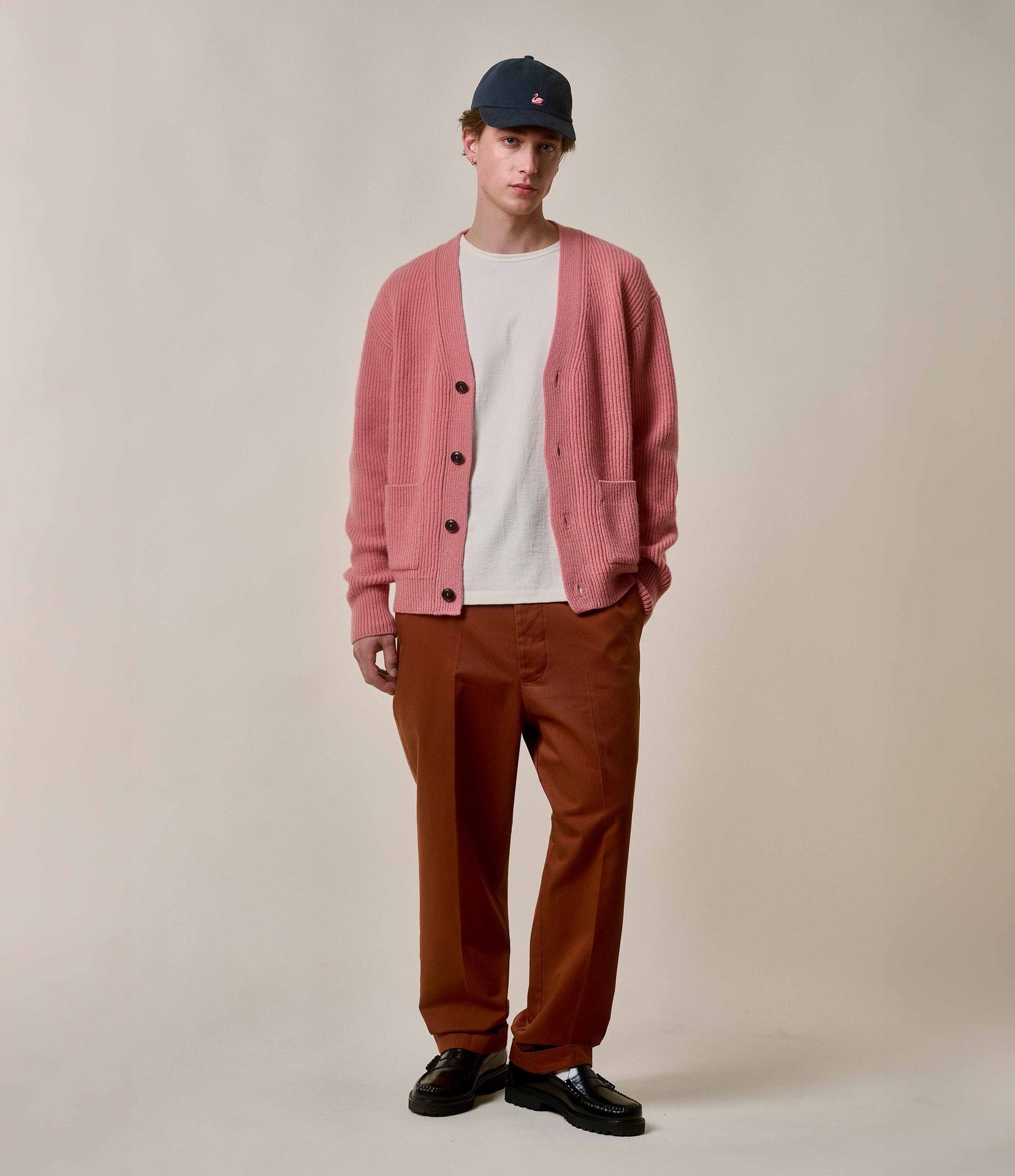 Man wearing pink knit cardigan and brown twill chinos