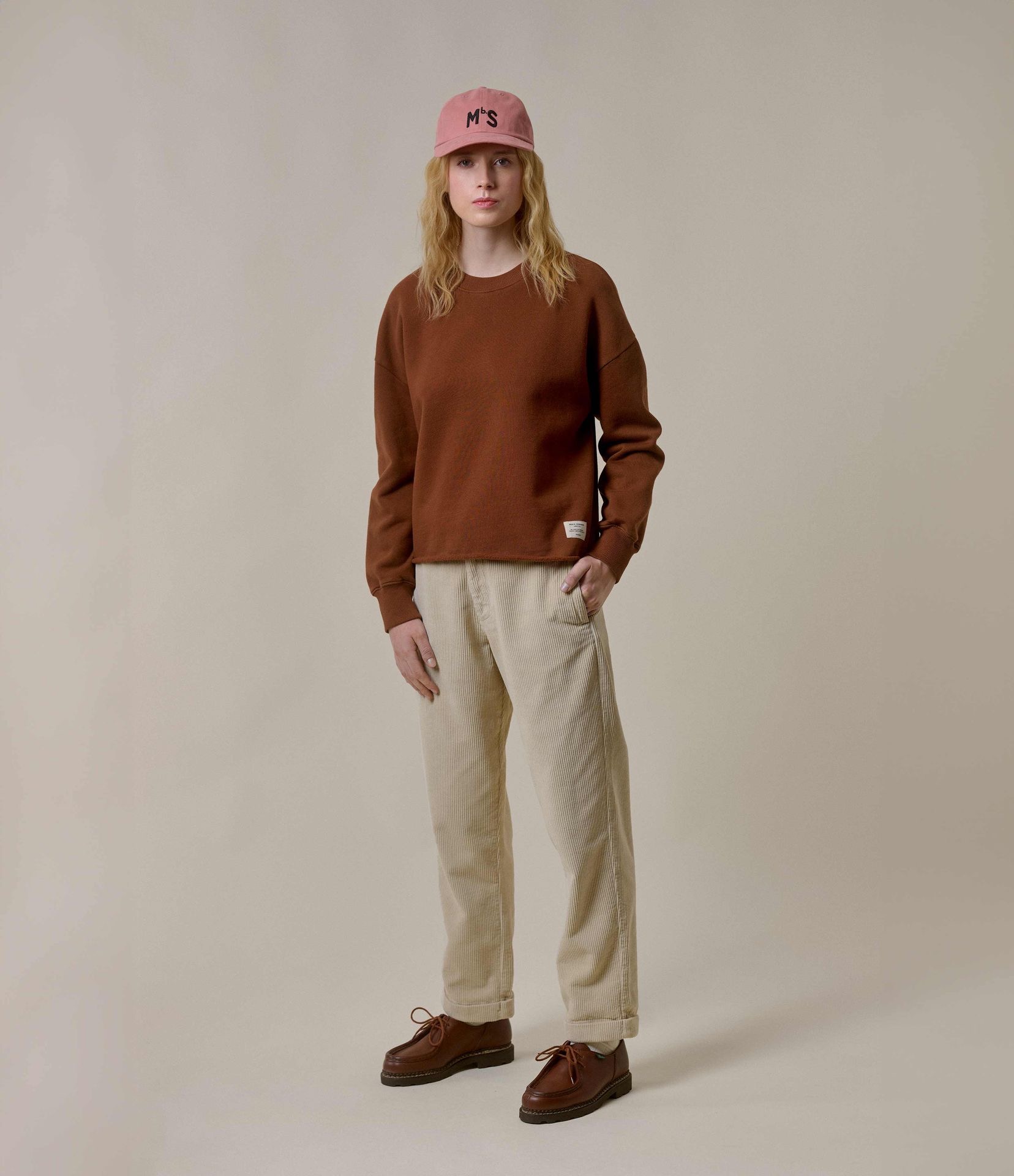 Woman wearing brown crewneck sweatshirt and ecru corduroy chinos