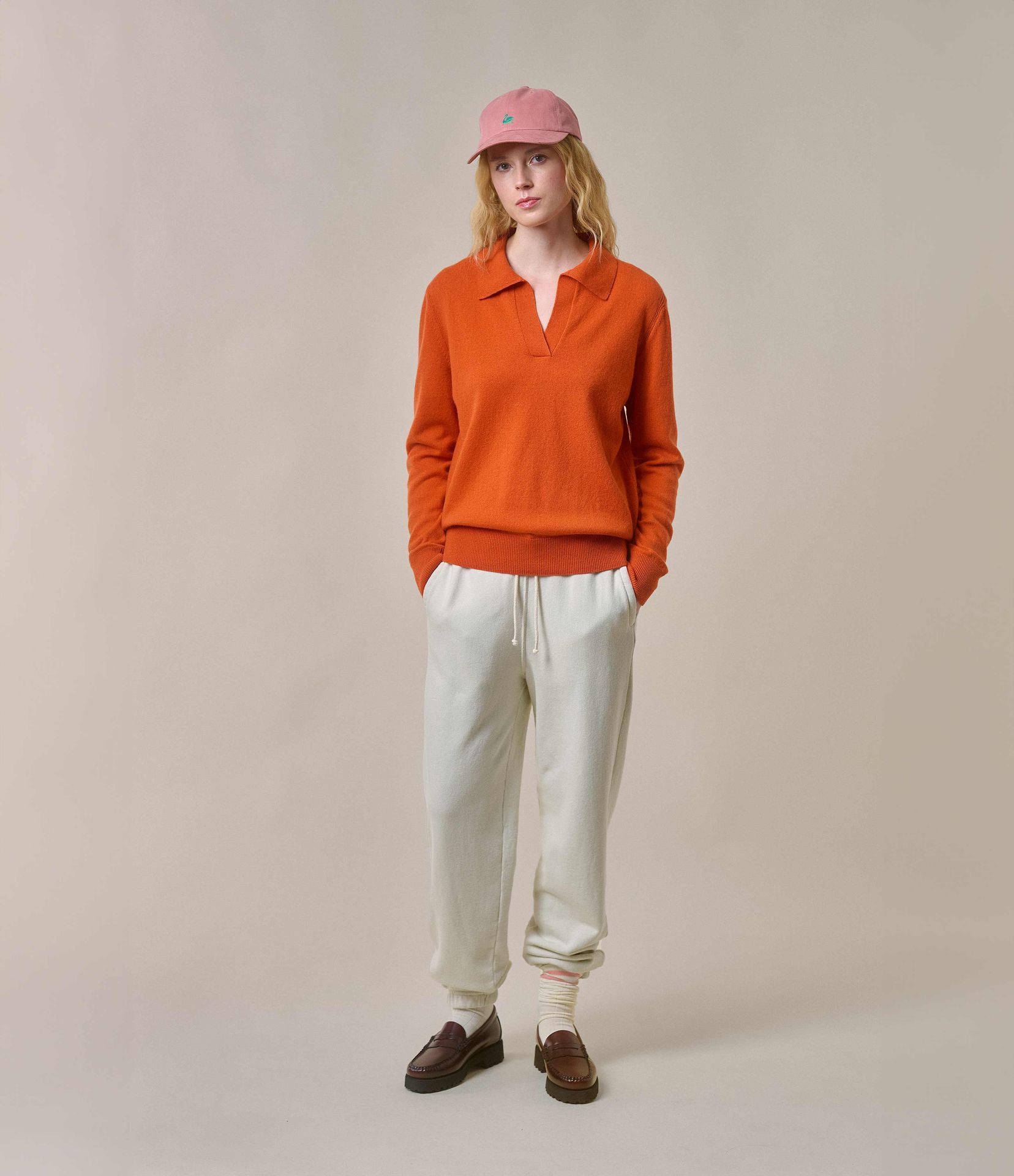 Woman wearing orange v-neck pullover and ecru sweatpants