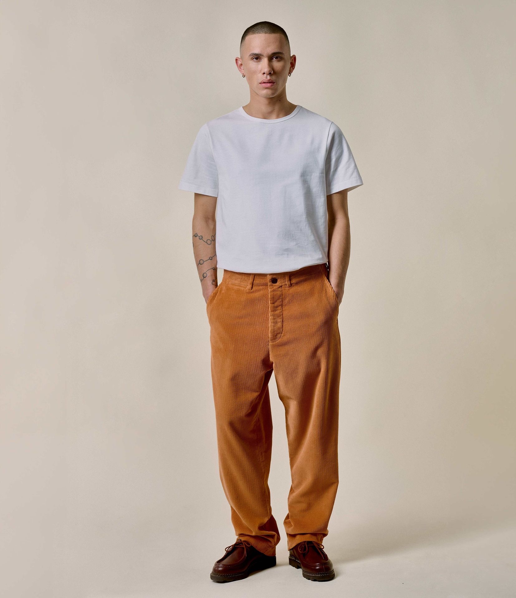 Man wearing white crewneck T-shirt and orange corduroy chinos