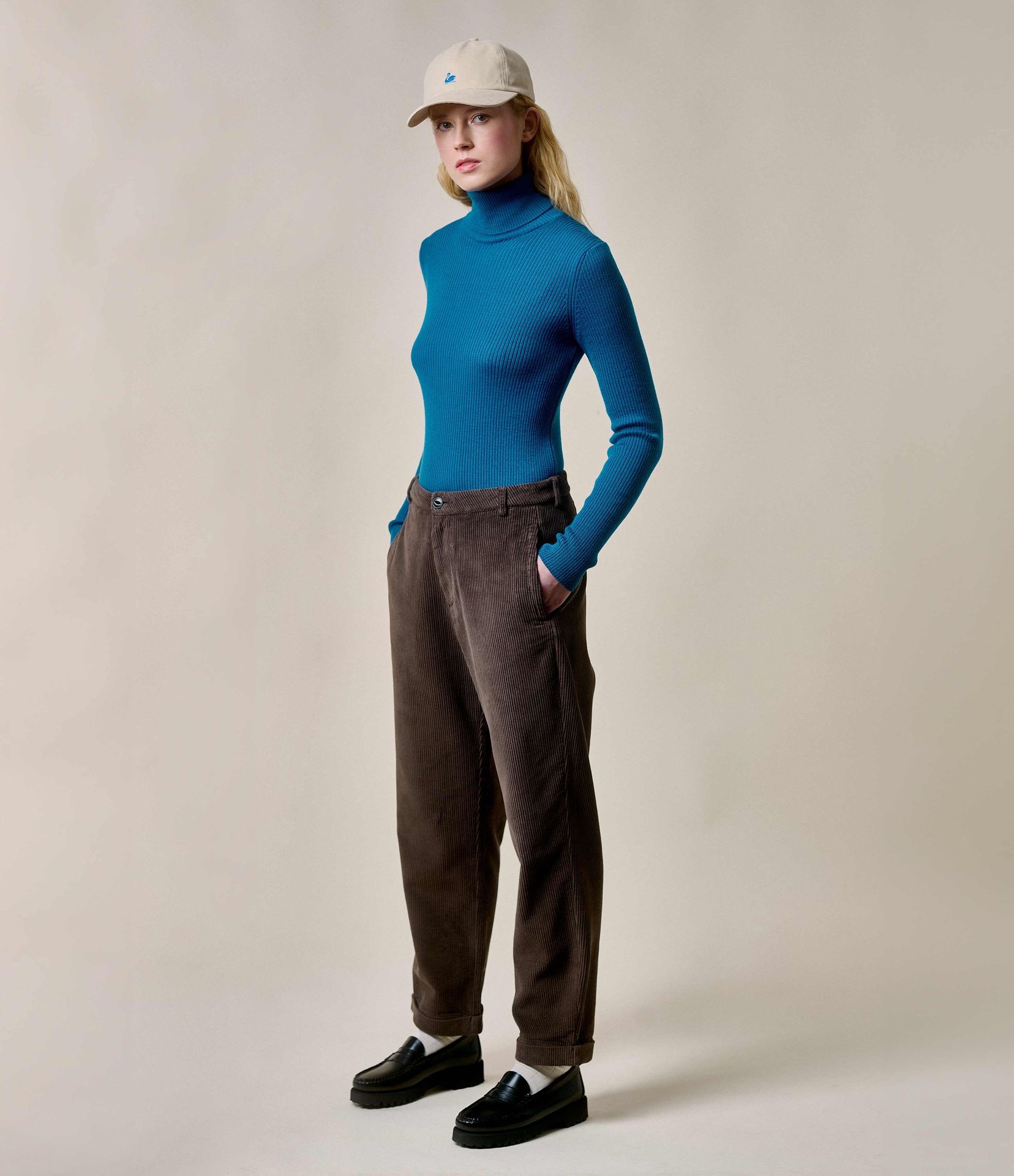Woman wearing blue turtleneck pullover and brown corduroy chinos