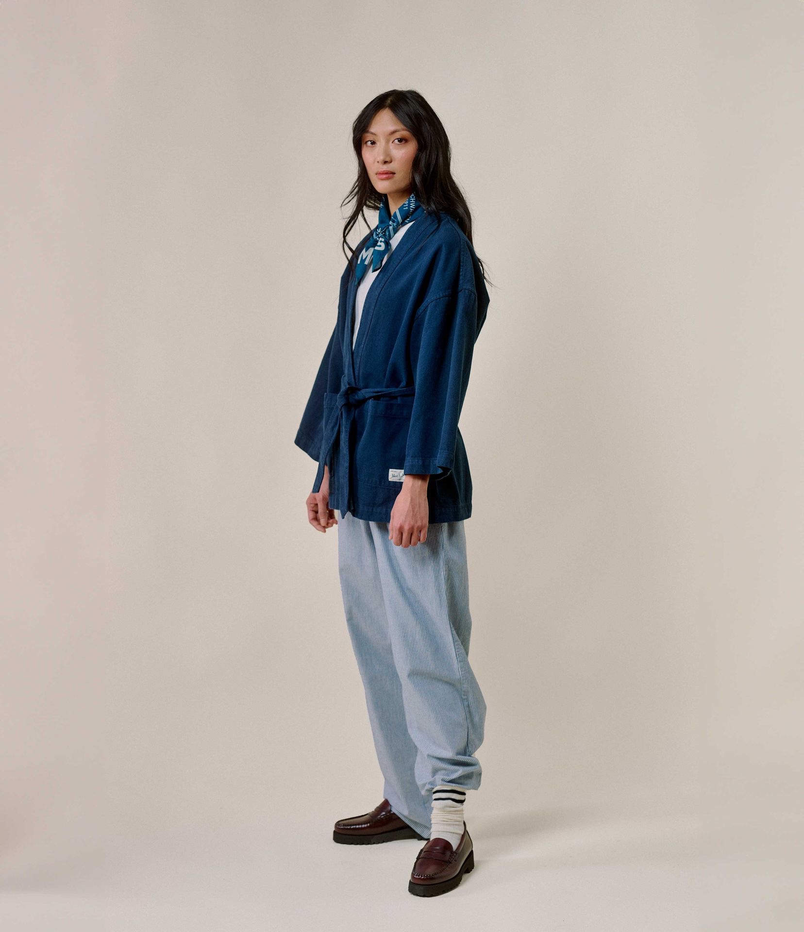 Woman wearing blue kimono-style jacket and striped pajama pants