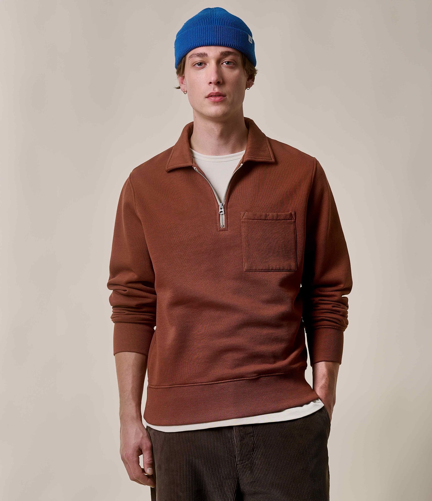 Man wearing brown half-zip sweatshirt and corduroy chinos