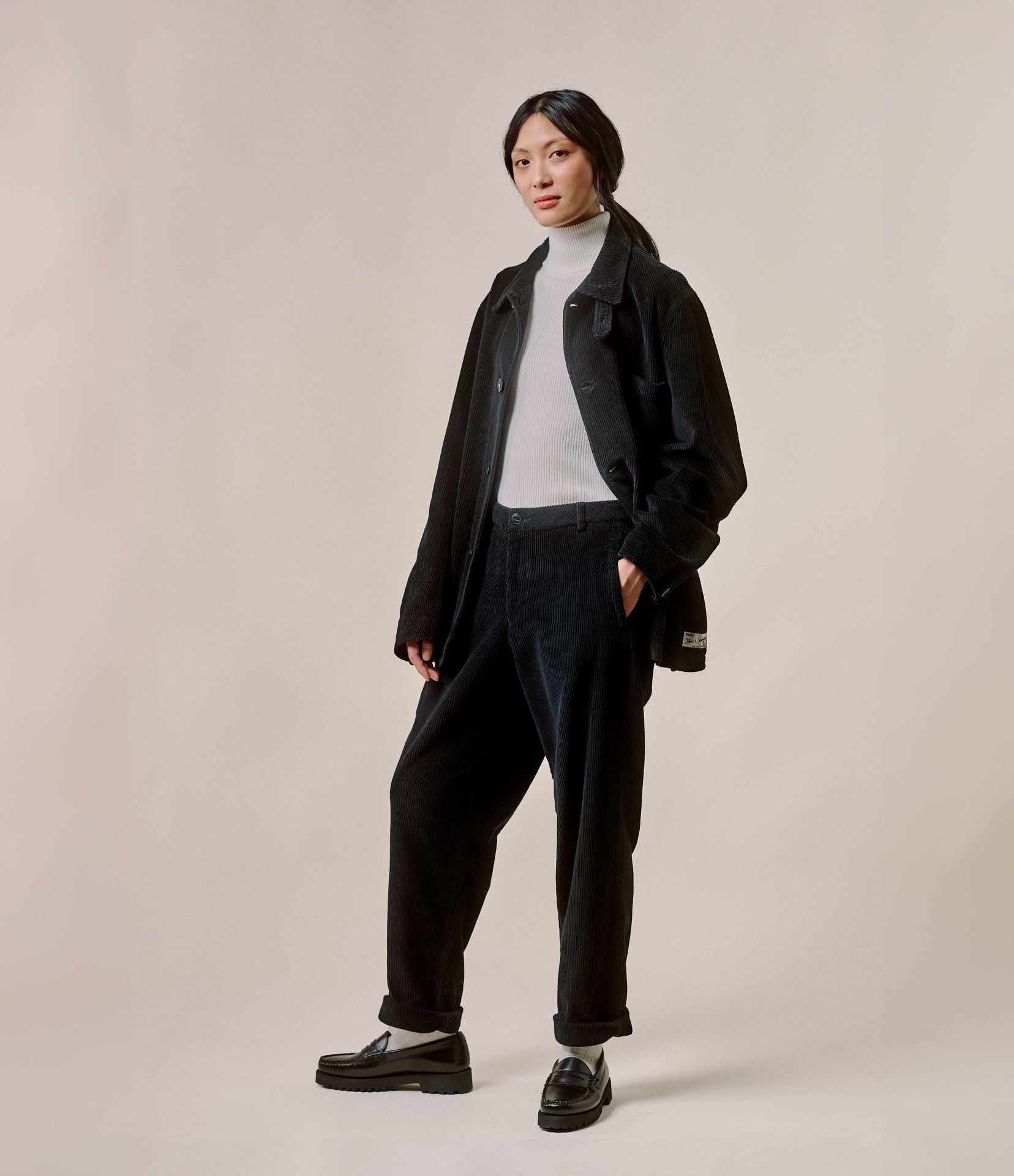 Woman wearing black corduroy jacket and chinos with ecru turtleneck