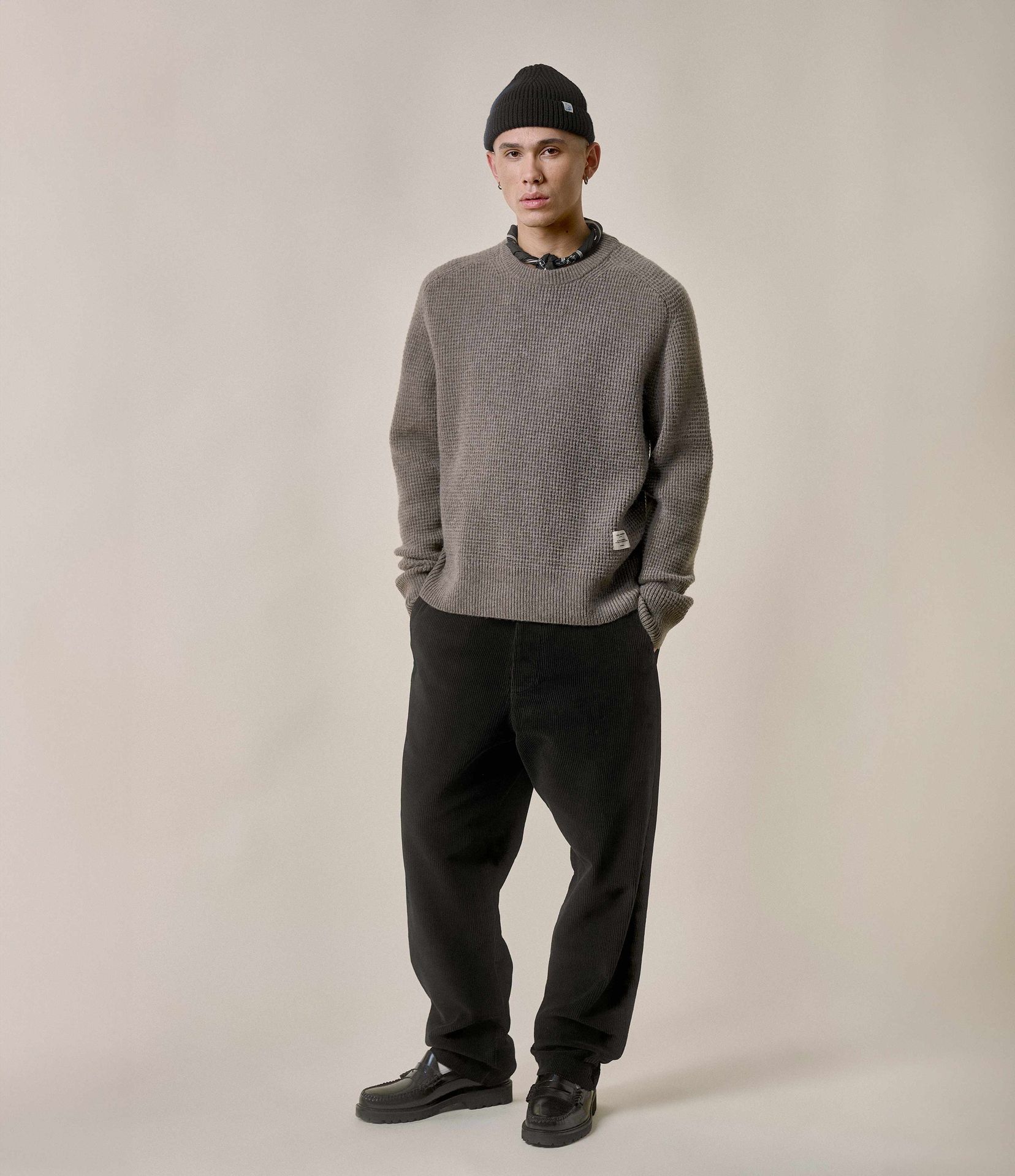 Man wearing grey waffle pullover and brown corduroy chinos