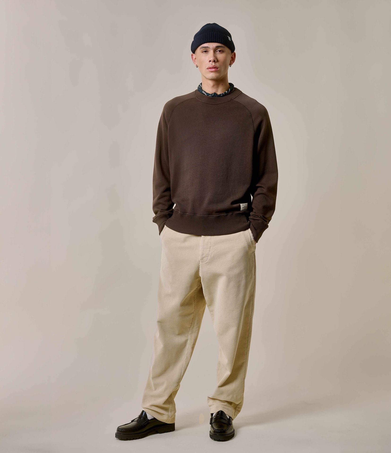 Man wearing brown crewneck sweatshirt and ecru corduroy chinos