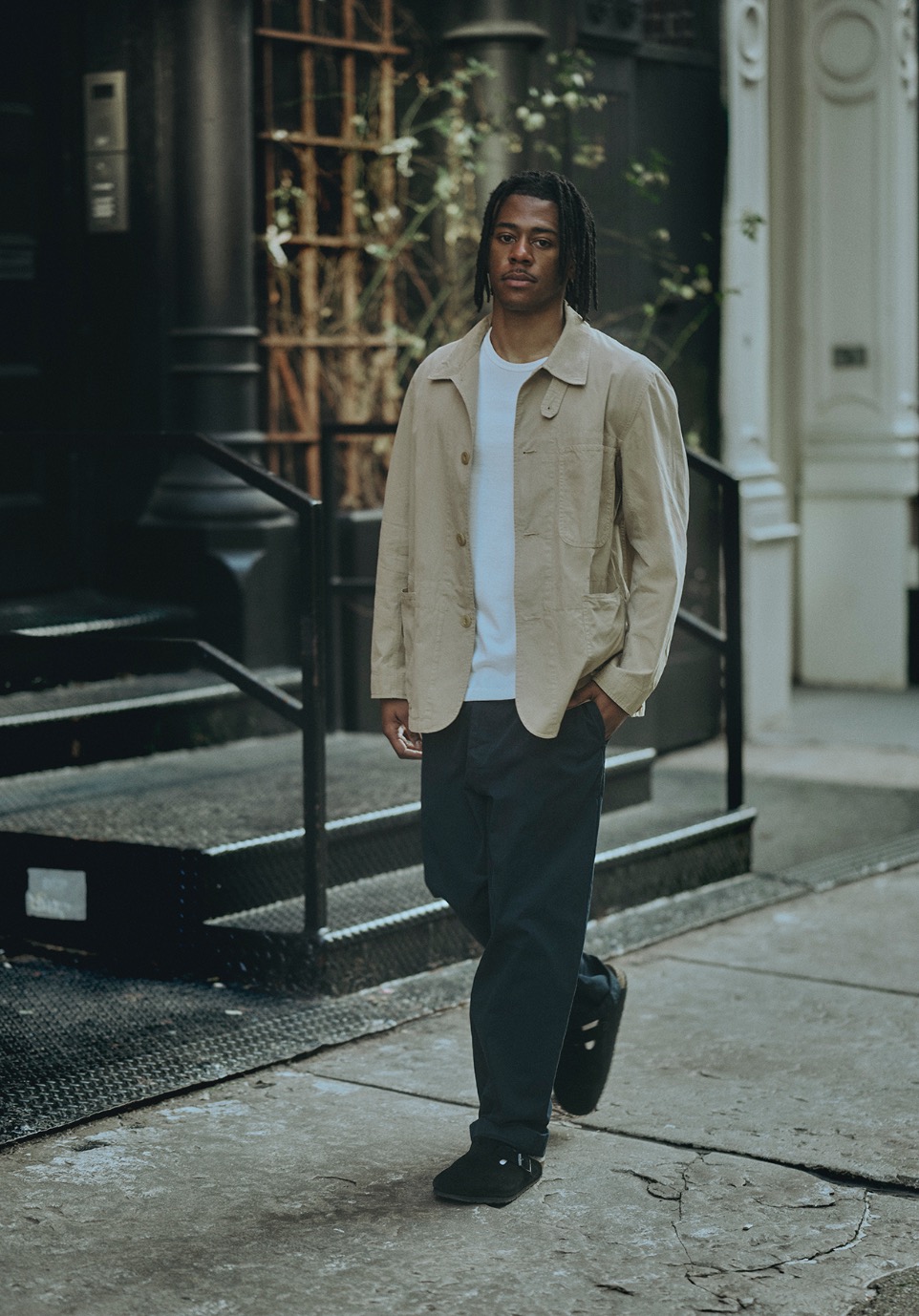 man wearing white t-shirt, khaki jacket and blue pants in the streets of New York