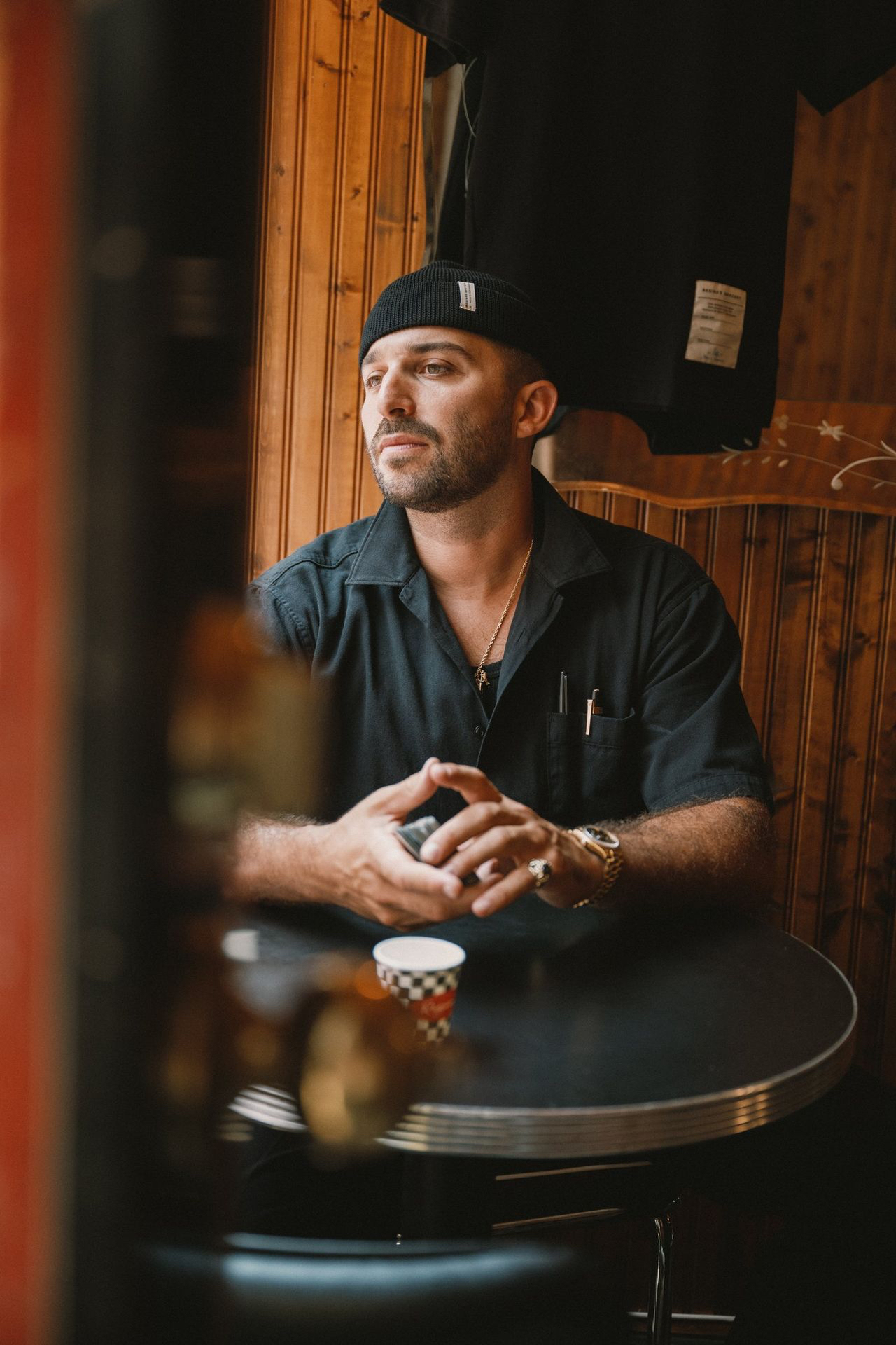 Man at a table wearing a black worker shirt and short beanie